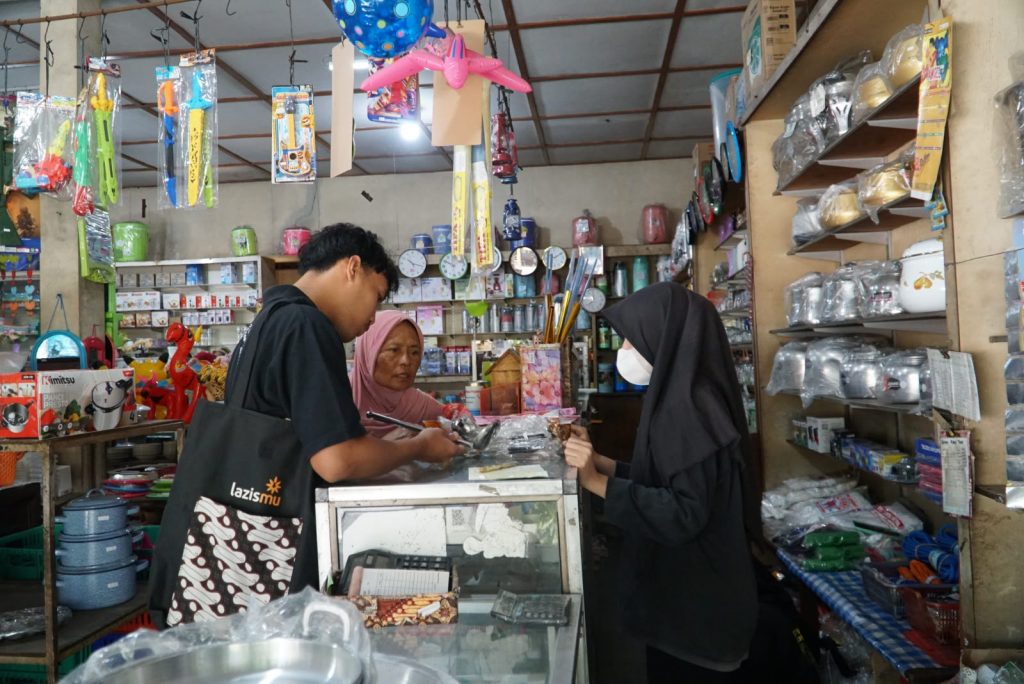 Yogyakarta — LAZISMU Daerah Istimewa Yogyakarta (DIY) kembali menyalurkan bantuan ekonomi produktif kepada pelaku usaha kecil melalui program pemberdayaan UMKM. Pada Sabtu (22/8/26), LAZISMU DIY melaksanakan pentasyarufan bantuan sekaligus branding usaha Angkringan Mamak milik Ibu Umani sebagai upaya mendukung pengembangan usaha dan kemandirian ekonomi keluarga. Angkringan Mamak berlokasi di Jalan Ringin Putih No. 7, Pringgan, Kotagede, DIY. Selama kurang lebih dua setengah tahun, Ibu Umani bersama suami dan salah satu anaknya telah menjalankan usaha tersebut yang buka setiap hari mulai pukul 05.00 hingga 13.00 WIB. Angkringan Mamak melayani berbagai kalangan, mulai dari warga sekitar, anak kos, petugas kebersihan, hingga anggota kepolisian. Pada jam-jam ramai, yakni sekitar pukul 07.00–10.00 WIB, angkringan ini mampu menjual lebih dari 30 bungkus nasi kucing per hari dengan harga Rp3.000 per bungkus. Selain itu, tersedia pula gorengan seharga Rp1.000, berbagai minuman, serta menu perususan yang berasal dari titipan. Dalam kesehariannya, usaha tersebut menjadi salah satu sumber penghasilan keluarga dengan pendapatan sekitar Rp300.000 per hari. Namun, masih terdapat sejumlah kendala yang menghambat perkembangan usaha, terutama keterbatasan peralatan dan pengelolaan keuangan yang belum tertata. Salah satu kebutuhan yang cukup mendesak adalah penambahan menu sayur. Permintaan tersebut datang dari sejumlah pelanggan, khususnya pihak kepolisian yang menjadi salah satu pelanggan Angkringan Mamak. Namun, keterbatasan modal membuat Ibu Umani belum dapat membeli perlengkapan yang diperlukan untuk menyiapkan menu tersebut. Melalui bantuan dari LAZISMU DIY, Angkringan Mamak mendapatkan dukungan berupa meja, tempat sayur, panci, wajan, serta tambahan modal usaha. Selain bantuan sarana dan modal, dilakukan pula branding pada angkringan agar tampil lebih menarik dan memiliki identitas usaha yang lebih kuat. Di sisi lain, pengelolaan keuangan menjadi salah satu hal yang perlu diperbaiki. Selama ini, uang hasil penjualan masih bercampur antara kebutuhan harian dan modal usaha sehingga keuntungan belum dapat terlihat secara jelas. Dengan pencatatan keuangan yang lebih tertib, Ibu Umani diharapkan dapat mengetahui perkembangan usaha, mengatur perputaran modal, serta merencanakan pengembangan usaha secara lebih baik. Bagi Ibu Umani, bantuan tersebut menjadi dukungan berarti untuk mengembangkan usaha yang selama ini dijalankan bersama keluarga. Ia berharap tambahan peralatan dan modal dapat membantu Angkringan Mamak memenuhi kebutuhan pelanggan sekaligus meningkatkan pendapatan usaha. “Harapannya, berkat bantuan dari LAZISMU ini bisa bermanfaat sampai seterusnya dan usaha saya semakin laris manis. Semoga ke depannya semuanya semakin lancar. Sekali lagi, terima kasih LAZISMU,” ungkap Ibu Umani. Program pentasyarufan ini menjadi bagian dari komitmen LAZISMU DIY dalam mendayagunakan dana zakat, infak, dan sedekah untuk mendorong kemandirian ekonomi masyarakat. Bantuan tidak hanya diberikan untuk memenuhi kebutuhan usaha, tetapi juga diarahkan agar penerima manfaat mampu mengembangkan usaha secara berkelanjutan. Dengan tambahan peralatan, modal, dan branding usaha tersebut, Angkringan Mamak diharapkan dapat berkembang, memenuhi permintaan pelanggan yang semakin beragam, meningkatkan omzet, serta memberikan manfaat yang lebih besar bagi keluarga Ibu Umani. LAZISMU DIY terus berkomitmen menghadirkan program pemberdayaan ekonomi yang tepat sasaran, sehingga dana zakat, infak, dan sedekah dapat menjadi penggerak kemandirian serta keberlanjutan usaha masyarakat kecil di Daerah Istimewa Yogyakarta.